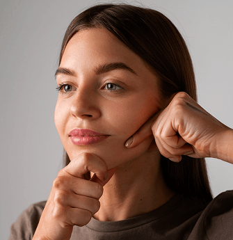 a woman gentling pinching her cheek and chin with both hands