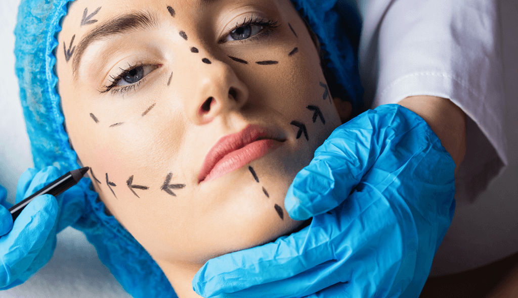 a doctor with blue gloves marking patients face before thread lift procedure